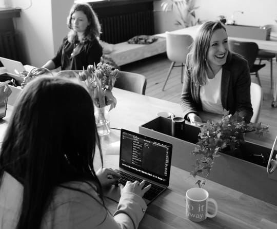 a small group of people working with laptops in an office environement